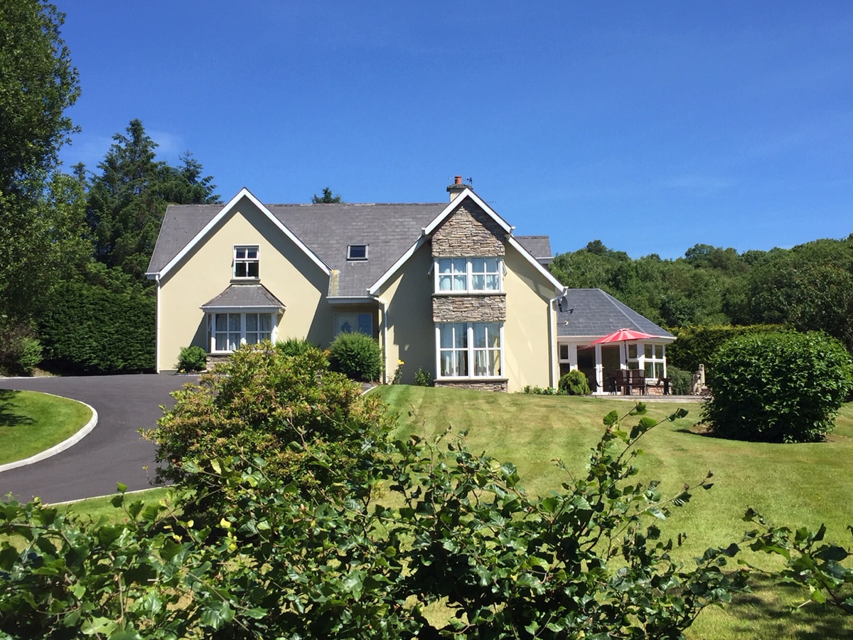 2 Mile Lodge surrounded by green gardens beneath a blue Kerry sky