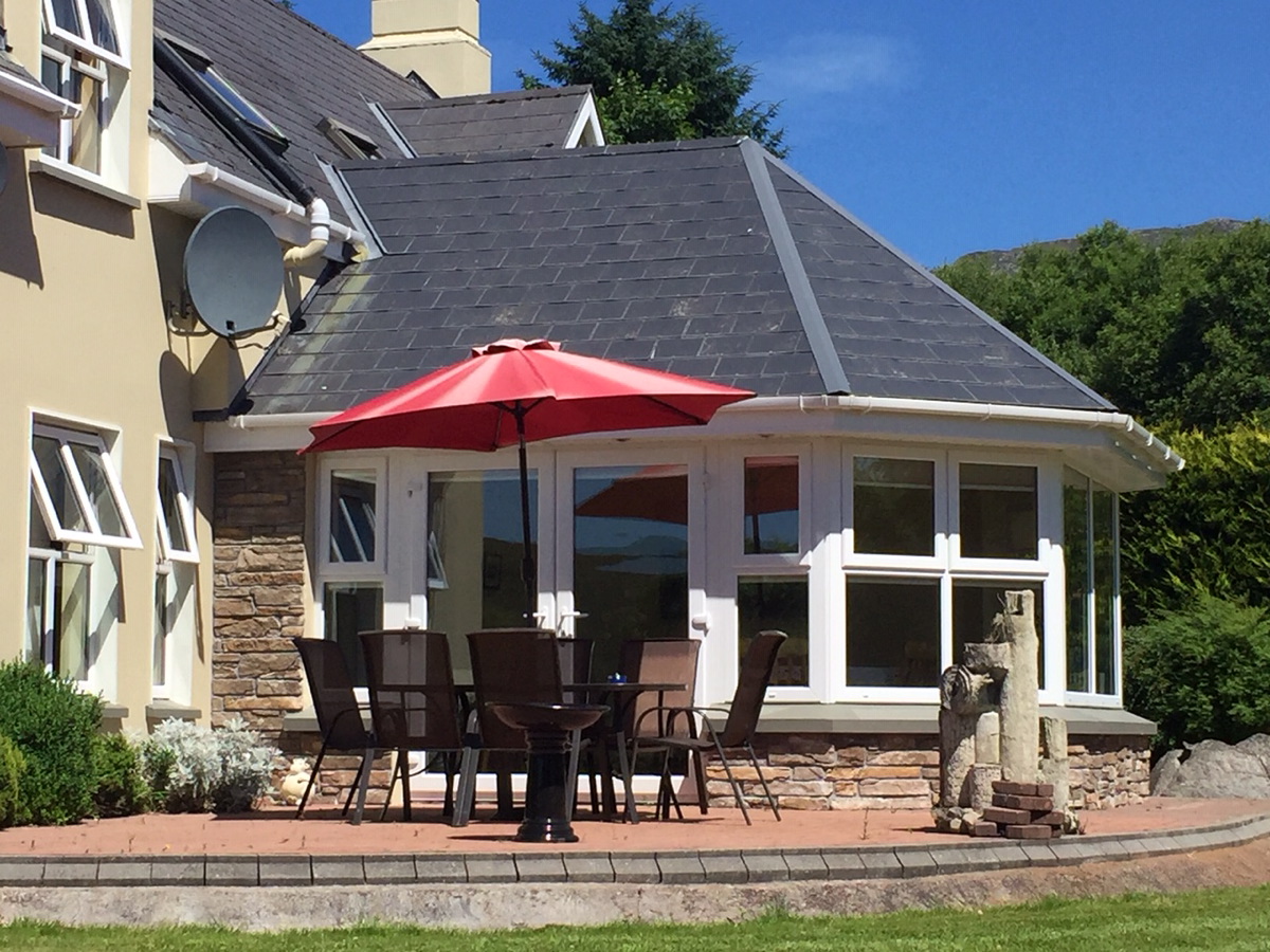 Outdoor seating and a red parasol beside the lodge conservatory